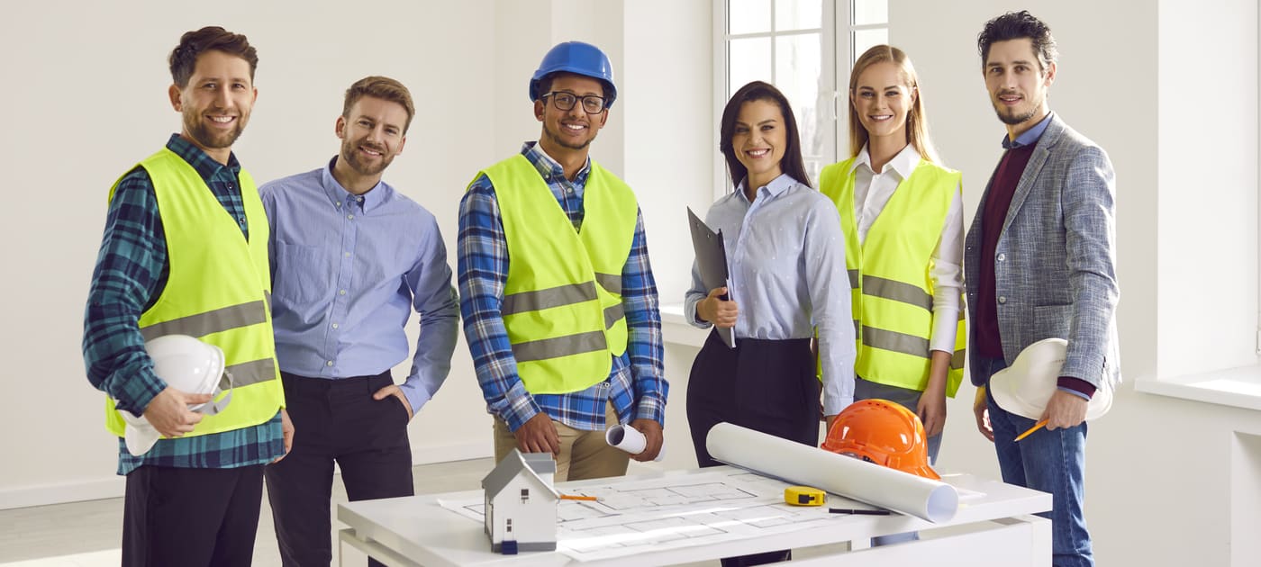 Six small business owners standing around a worktable with blueprints